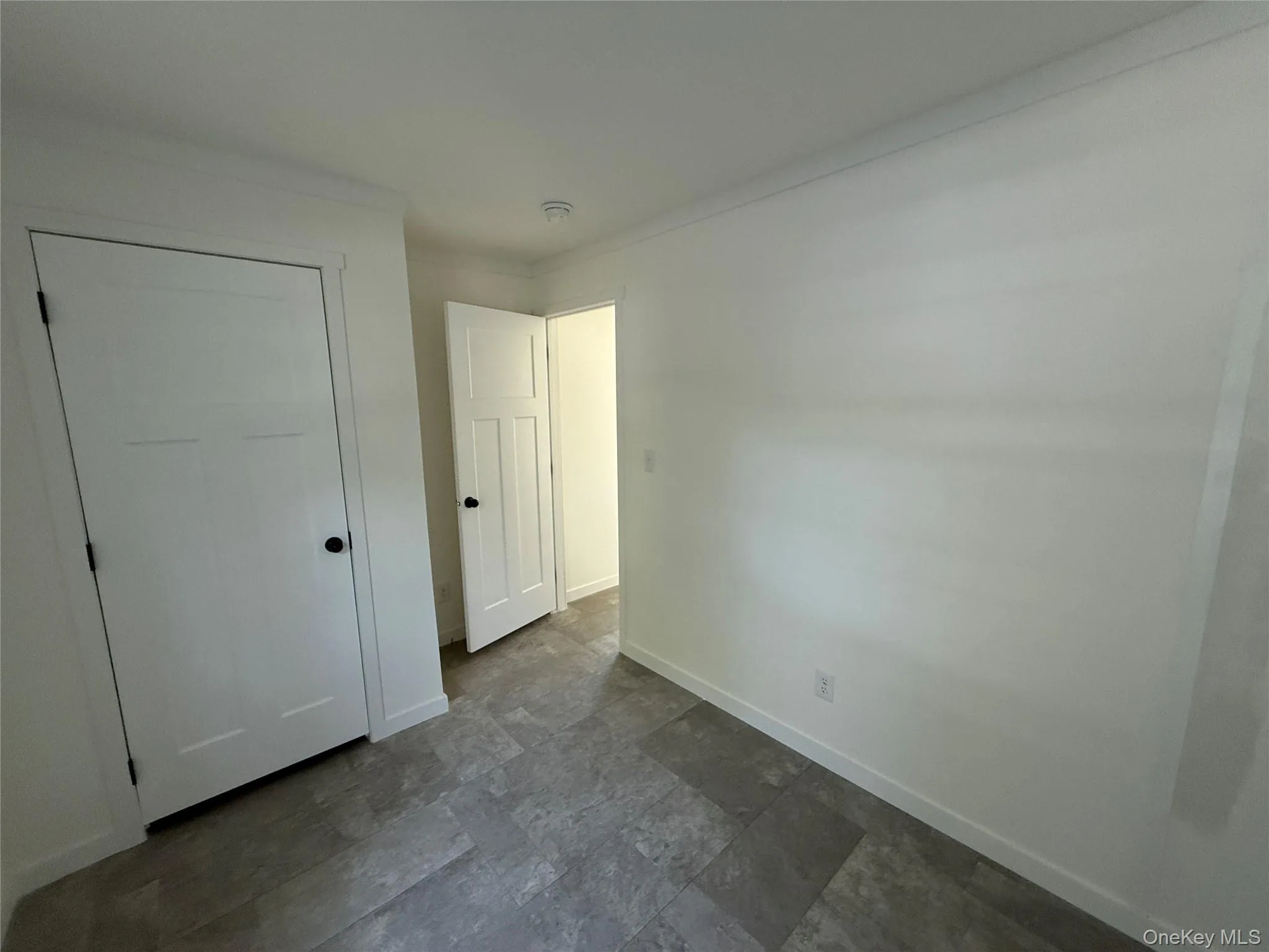 Unfurnished bedroom with ornamental molding, dark stone finish floors, and a closet Unfurnished bedroom with ornamental molding, dark stone finish floors, and a closet