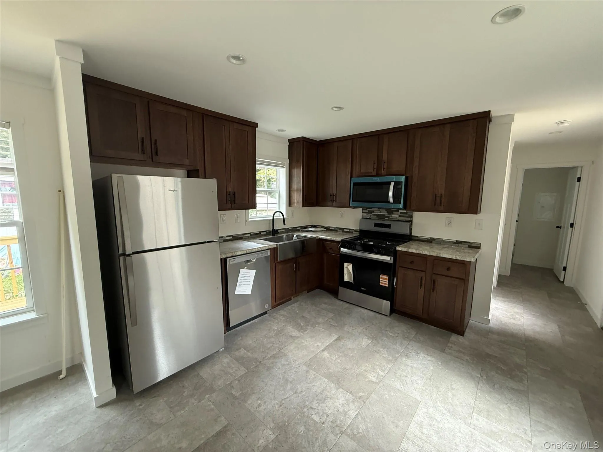 Kitchen featuring stainless steel appliances, dark brown cabinetry, stone finish floors, light countertops, and recessed lighting Kitchen featuring stainless steel appliances, dark brown cabinetry, stone finish floors, light countertops, and recessed lighting