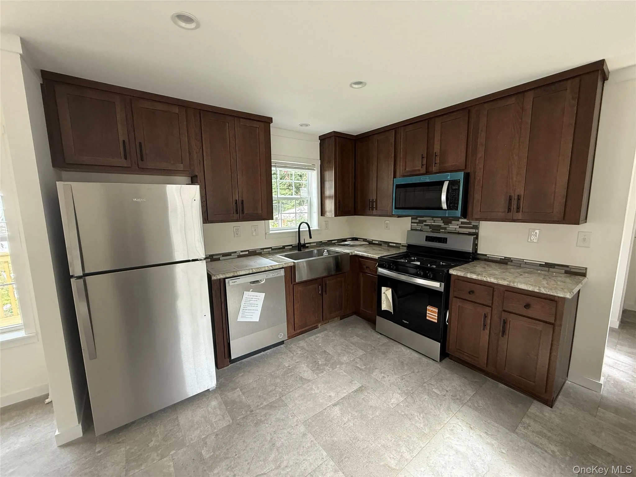 Kitchen featuring dark brown cabinetry, stainless steel appliances, recessed lighting, and tasteful backsplash Kitchen featuring dark brown cabinetry, stainless steel appliances, recessed lighting, and tasteful backsplash