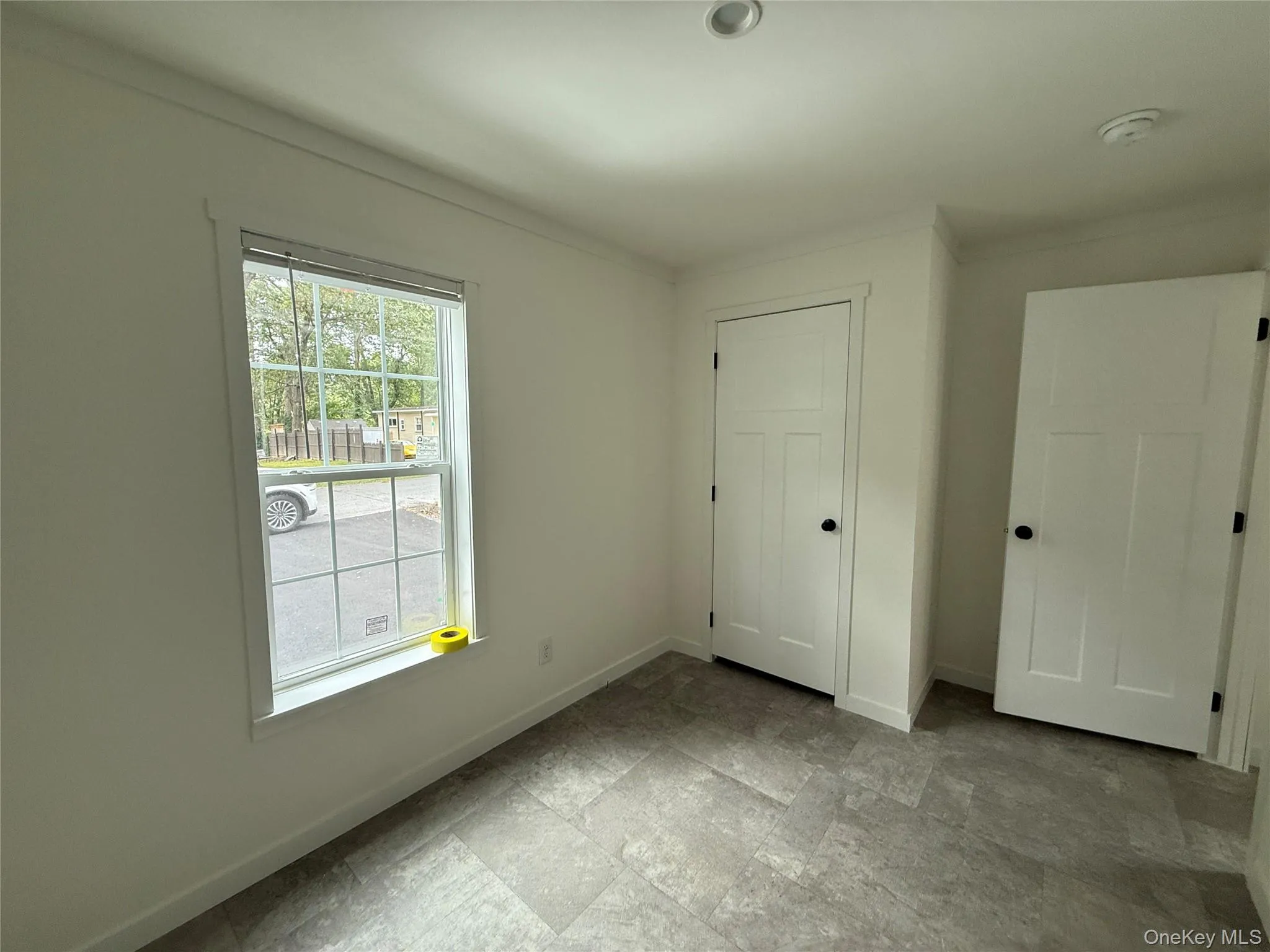 Unfurnished bedroom featuring a closet, ornamental molding, and light stone finish flooring Unfurnished bedroom featuring a closet, ornamental molding, and light stone finish flooring