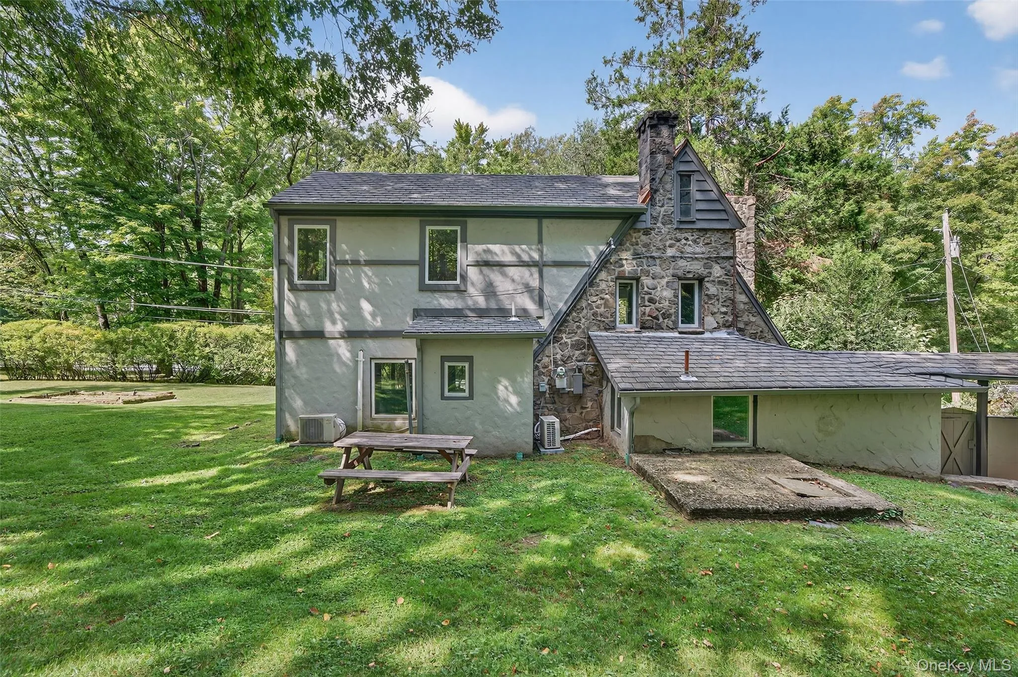 Back of property with stucco siding, a yard, a chimney, and view of scattered trees Back of property with stucco siding, a yard, a chimney, and view of scattered trees