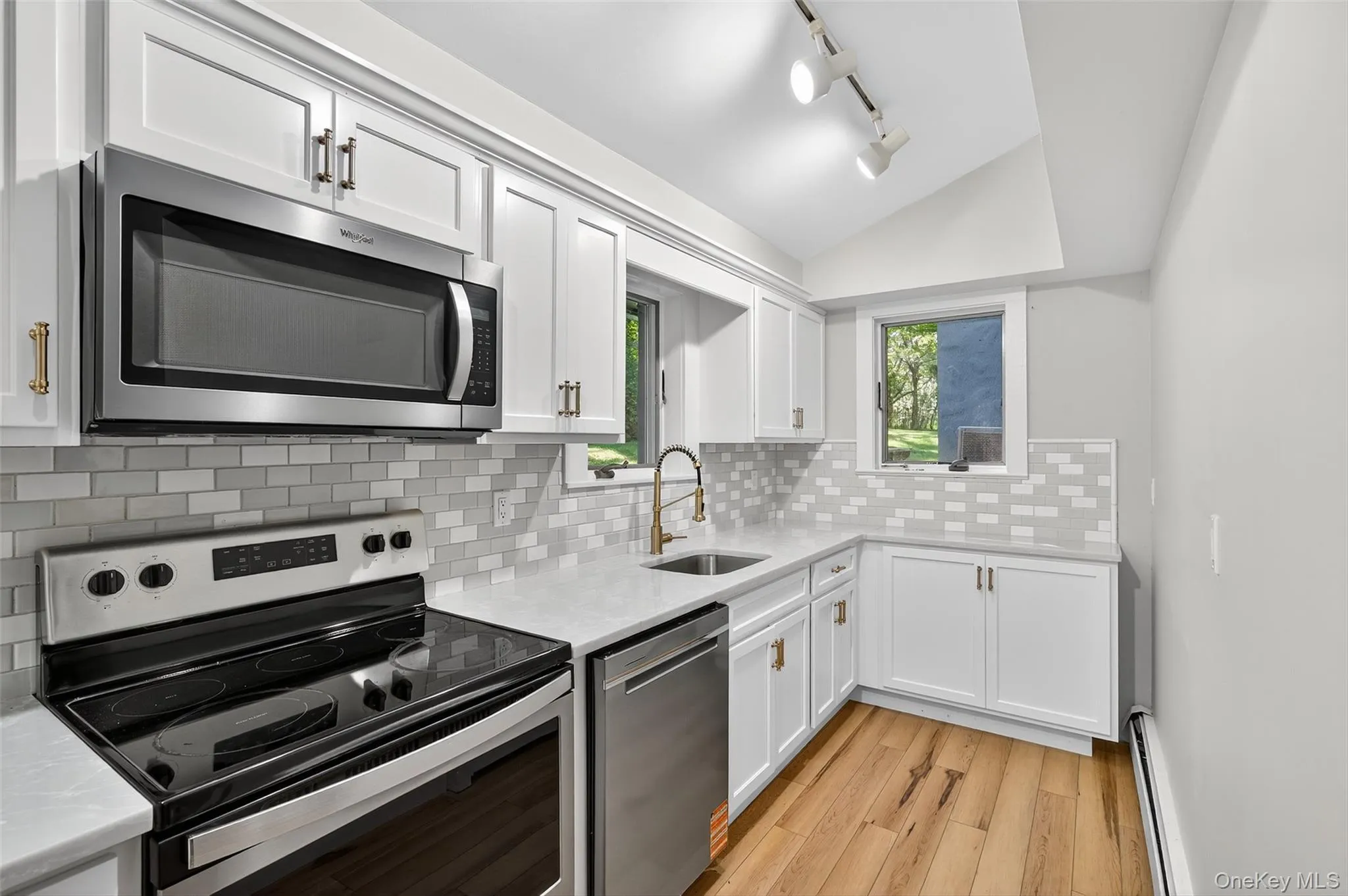 Renovated kitchen with stainless steel appliances, deep sink, vaulted ceiling and quartz counters. Light wood-style floors Renovated kitchen with stainless steel appliances, deep sink, vaulted ceiling and quartz counters. Light wood-style floors