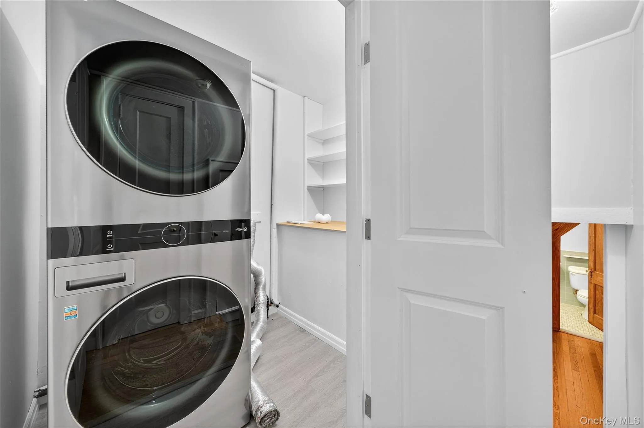 Laundry room in the hall with standard sized, stacked washer and dryer. Laundry room in the hall with standard sized, stacked washer and dryer.