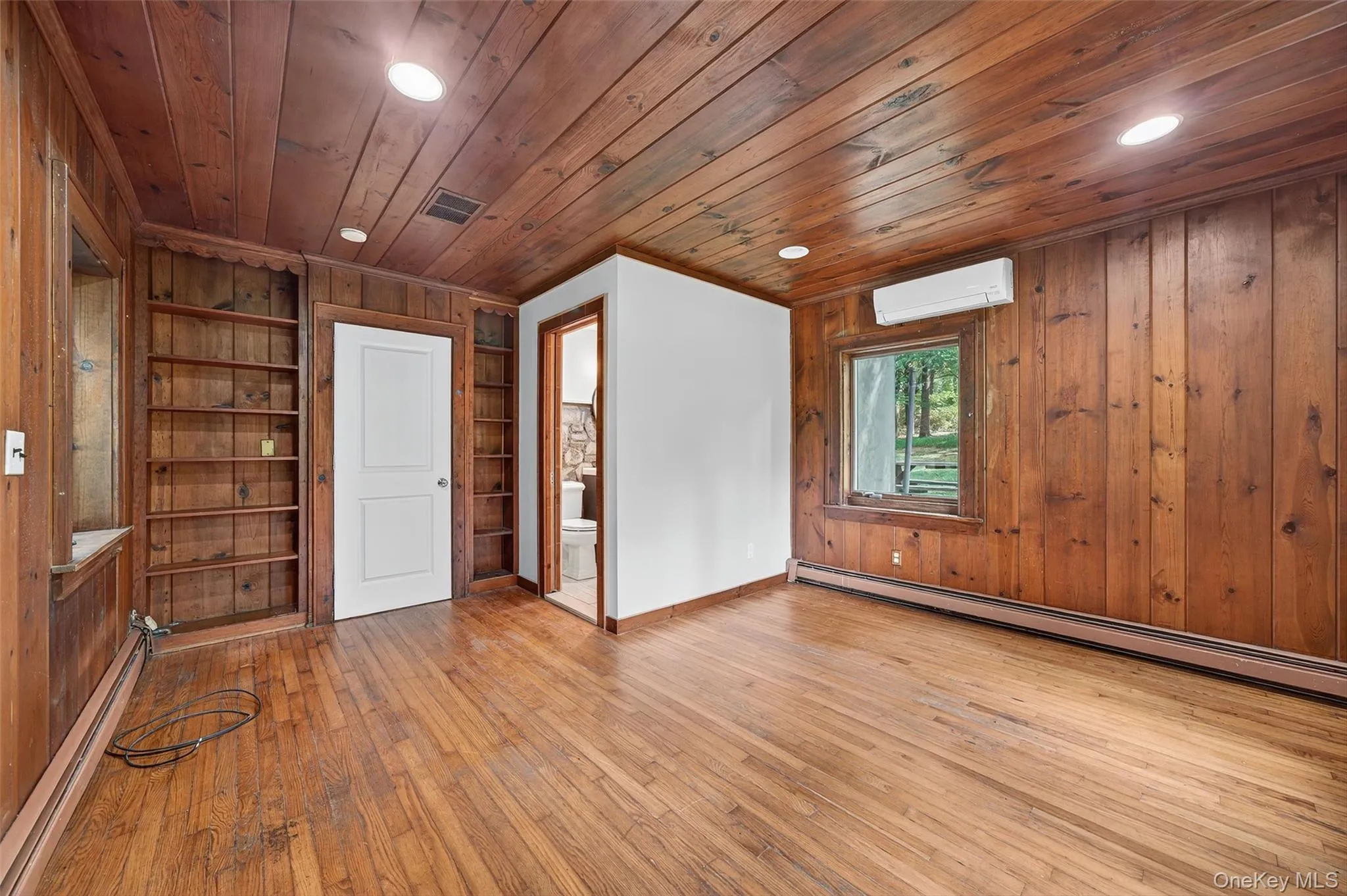 featuring built in shelves, bath room, and wood floor featuring built in shelves, bath room, and wood floor