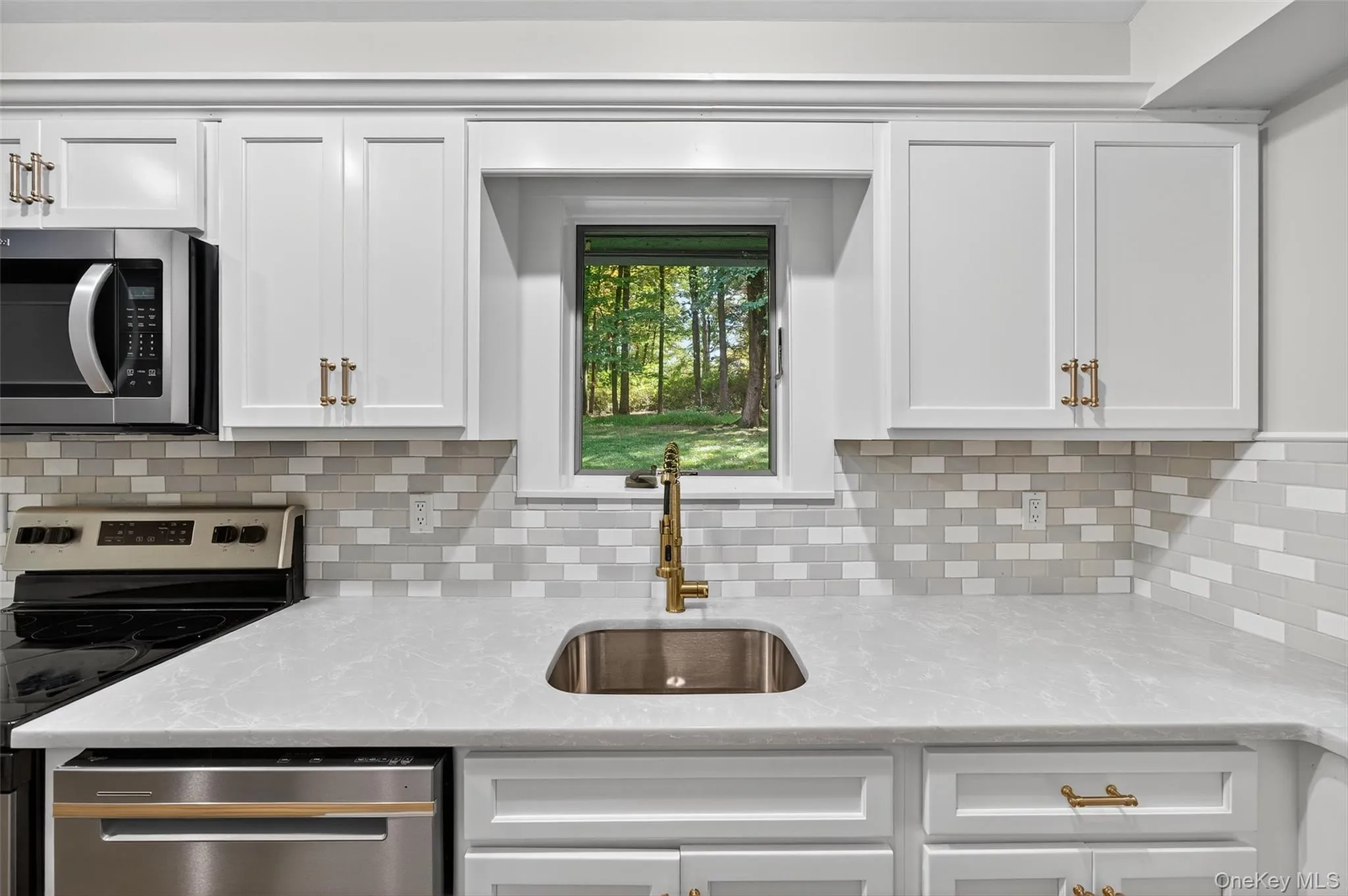 Full on photo with tasteful backsplash, light quartz counters, and white cabinetry Full on photo with tasteful backsplash, light quartz counters, and white cabinetry