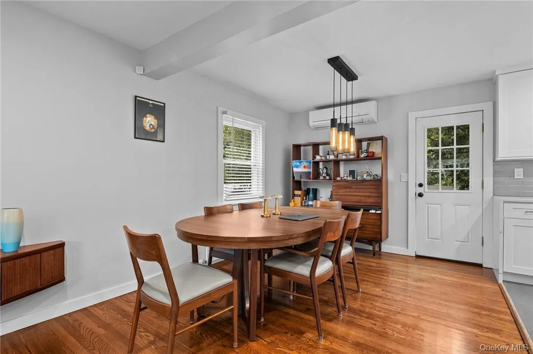 Dining space featuring an inviting chandelier, light hardwood / wood-style flooring, and an AC wall unit Dining space featuring an inviting chandelier, light hardwood / wood-style flooring, and an AC wall unit