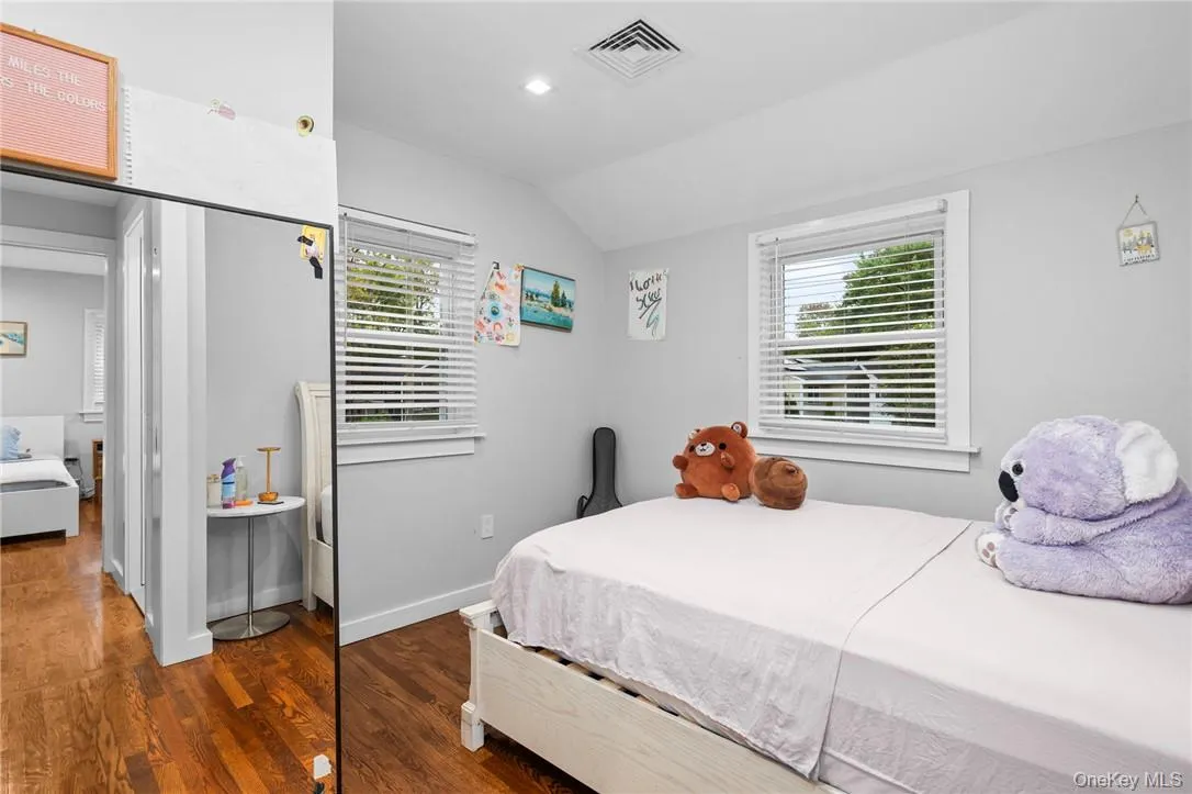 Bedroom with lofted ceiling, multiple windows, and dark hardwood / wood-style floors Bedroom with lofted ceiling, multiple windows, and dark hardwood / wood-style floors