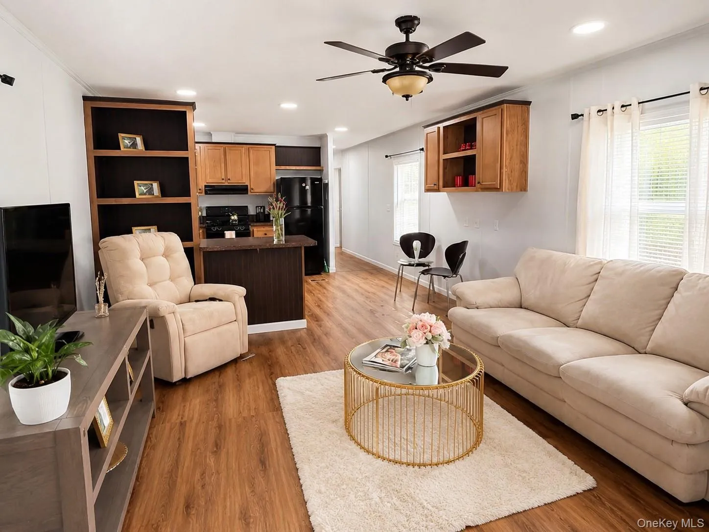 Open-concept living area featuring wood-finish flooring, a ceiling fan with integrated lighting, recessed lighting, and ample natural light from multiple windows Open-concept living area featuring wood-finish flooring, a ceiling fan with integrated lighting, recessed lighting, and ample natural light from multiple windows