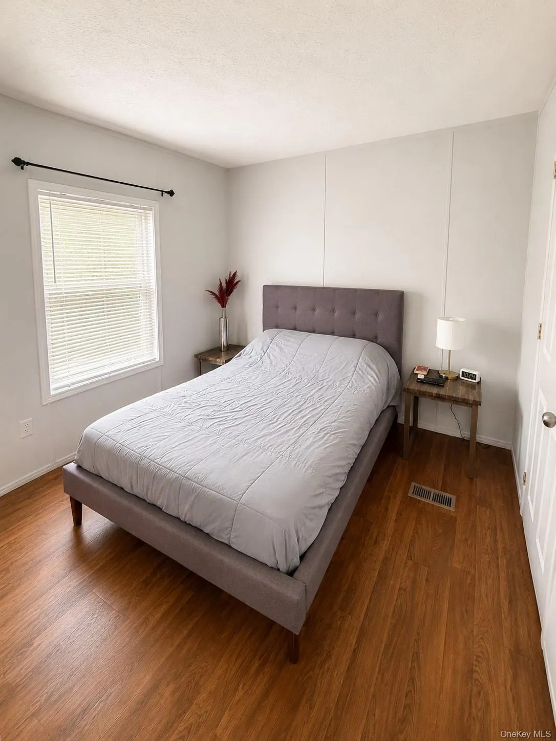 Room featuring wood-finish flooring, a window with blinds, and white walls Room featuring wood-finish flooring, a window with blinds, and white walls