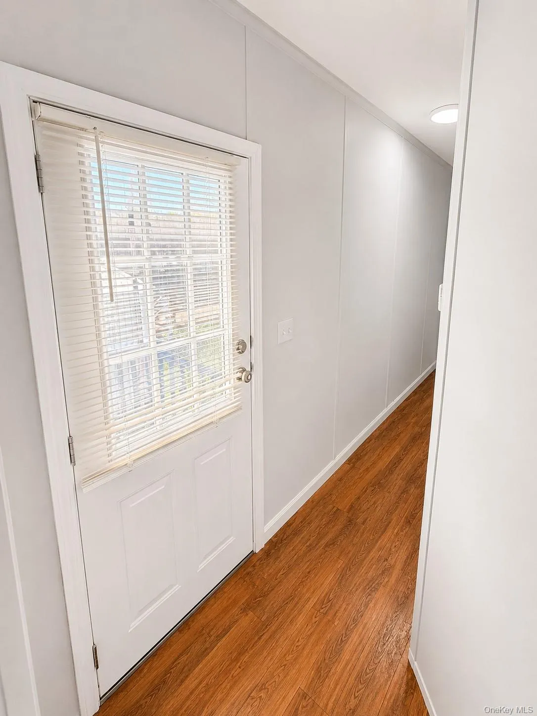 Entryway featuring a white paneled door with glass insert, wood-finish flooring, and recessed ceiling lighting Entryway featuring a white paneled door with glass insert, wood-finish flooring, and recessed ceiling lighting