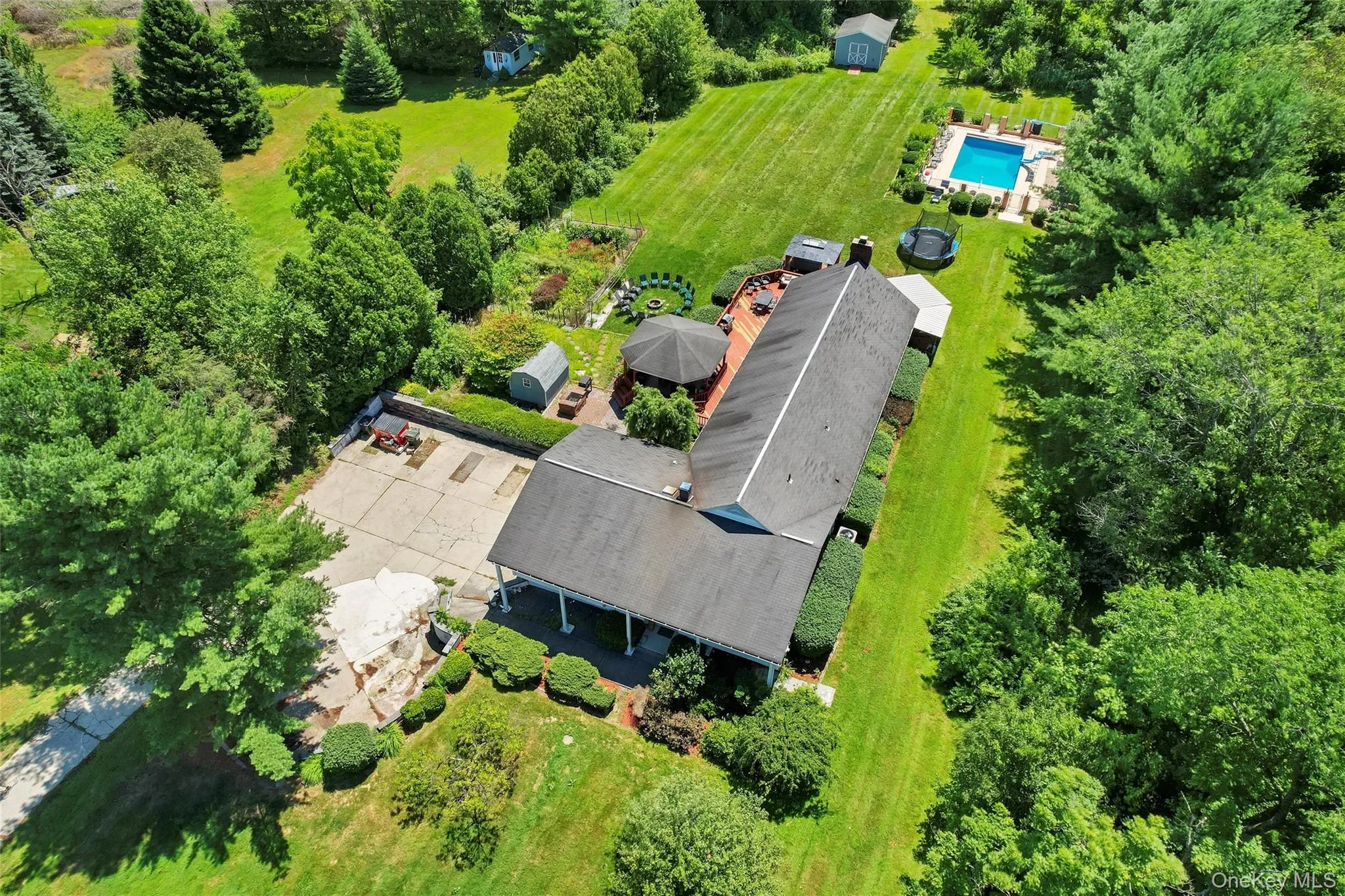Expansive outdoor property featuring a rectangular in-ground pool, a spacious wood deck, and a multi-car driveway Expansive outdoor property featuring a rectangular in-ground pool, a spacious wood deck, and a multi-car driveway