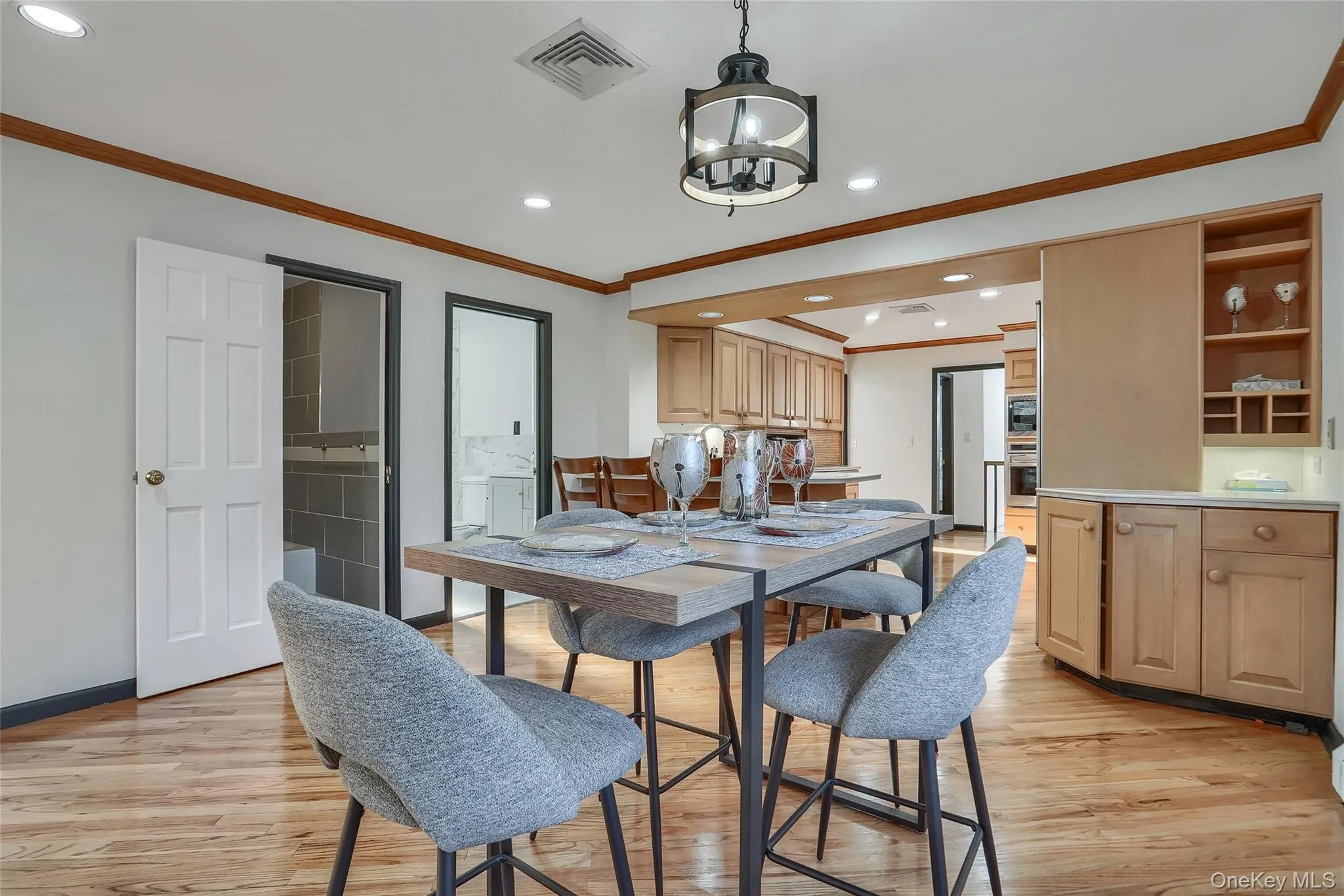 Dining area featuring wood-finish flooring, a contemporary chandelier, recessed lighting, and a built-in buffet with open shelving and lower cabinetry Dining area featuring wood-finish flooring, a contemporary chandelier, recessed lighting, and a built-in buffet with open shelving and lower cabinetry