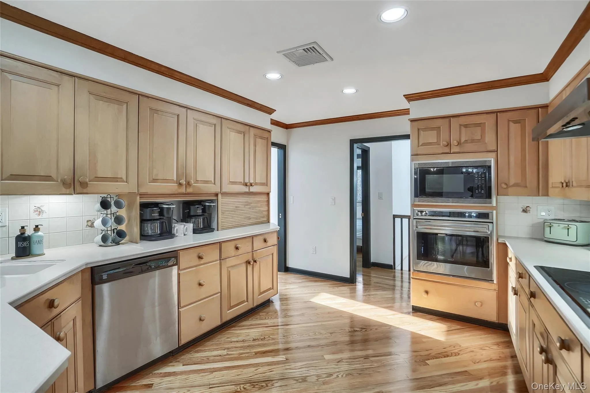 Kitchen featuring wood-finish flooring, light wood cabinetry, recessed lighting, and stainless steel built-in appliances Kitchen featuring wood-finish flooring, light wood cabinetry, recessed lighting, and stainless steel built-in appliances