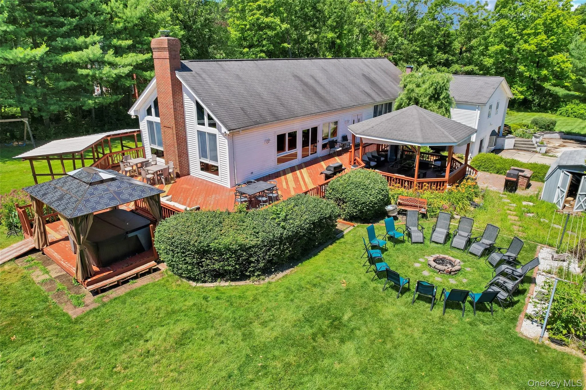 Expansive backyard featuring a central fire pit, two wooden gazebos, and a multi-level wood deck Expansive backyard featuring a central fire pit, two wooden gazebos, and a multi-level wood deck