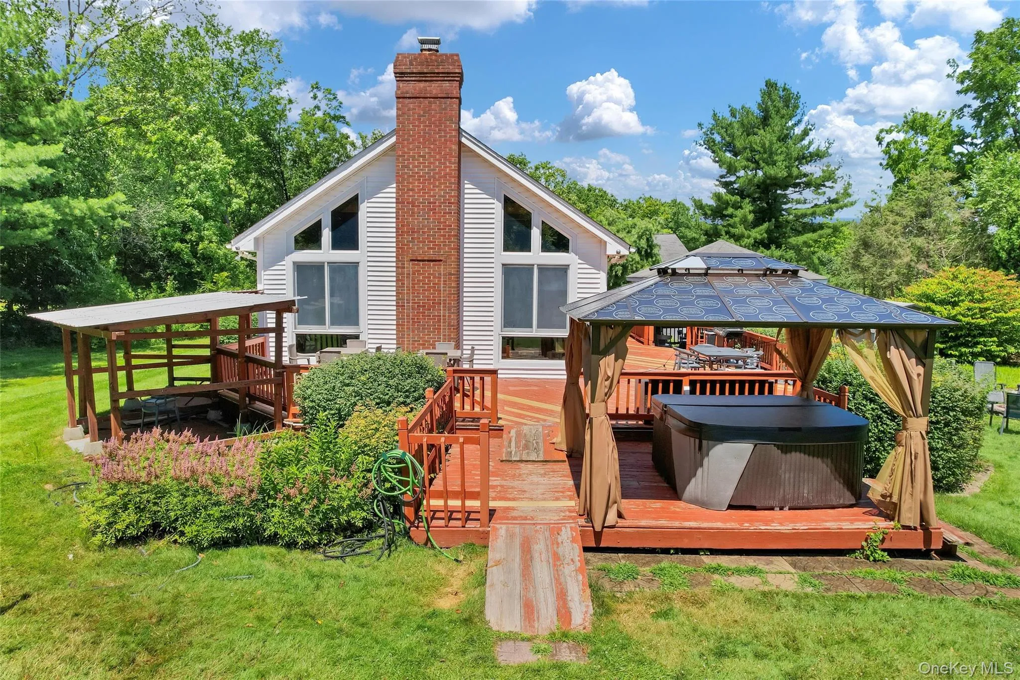 Expansive rear deck featuring a hot tub within a covered gazebo Expansive rear deck featuring a hot tub within a covered gazebo