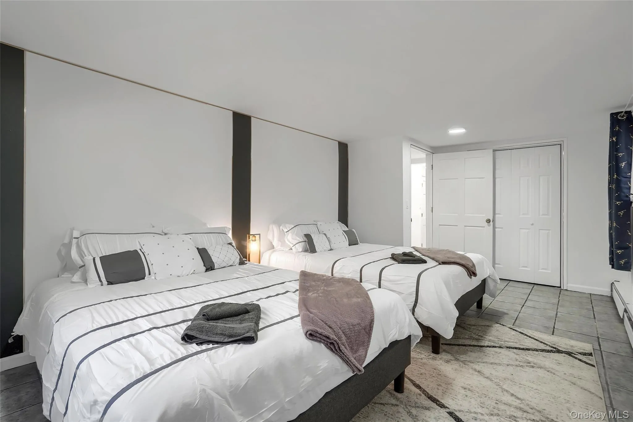 Spacious room featuring neutral walls with dark accent panels, recessed lighting, and durable tile flooring Spacious room featuring neutral walls with dark accent panels, recessed lighting, and durable tile flooring