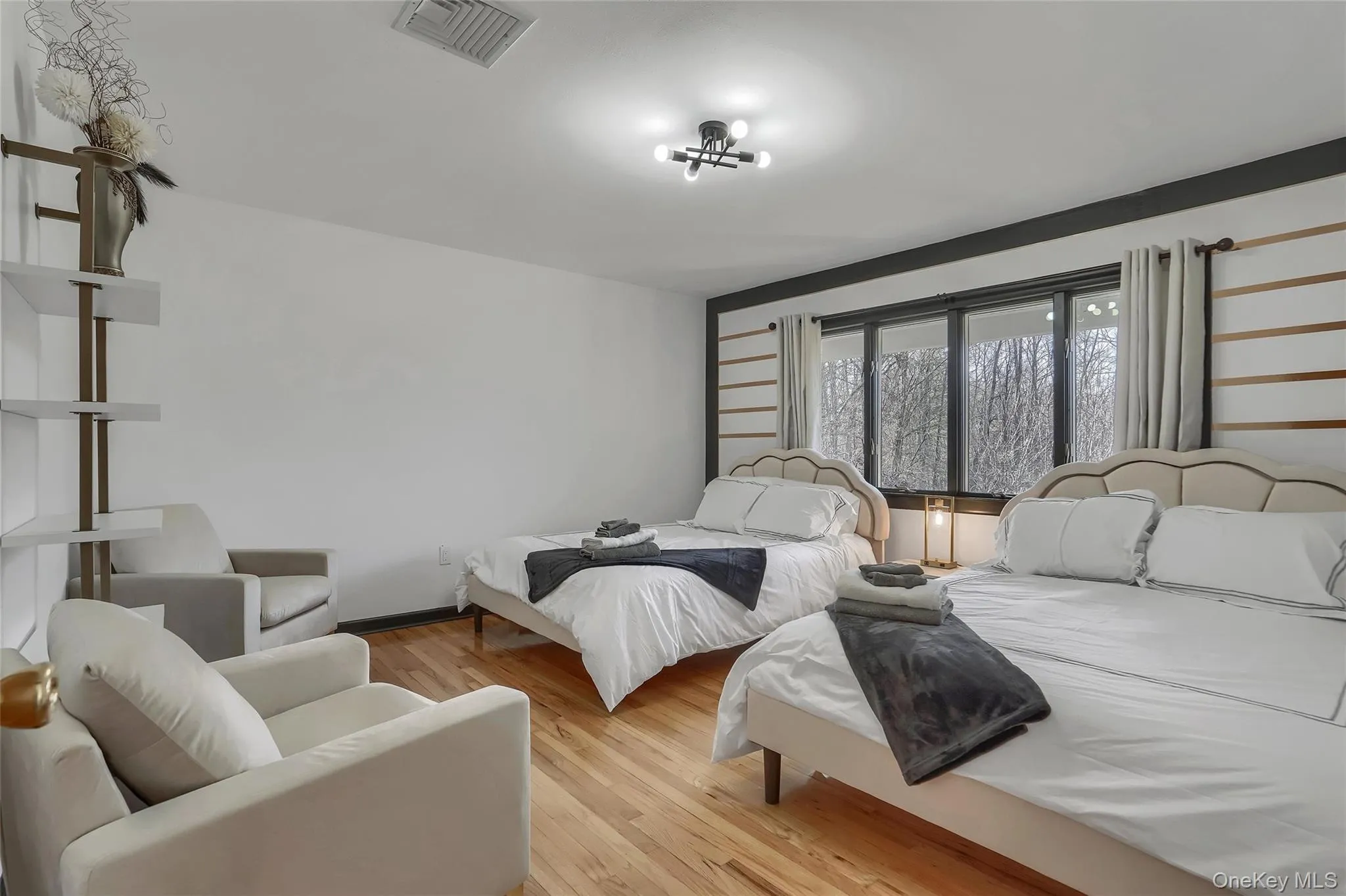 Hardwood flooring, large windows, ceiling-mounted light fixture, built-in shelving, and two upholstered bed frames Hardwood flooring, large windows, ceiling-mounted light fixture, built-in shelving, and two upholstered bed frames