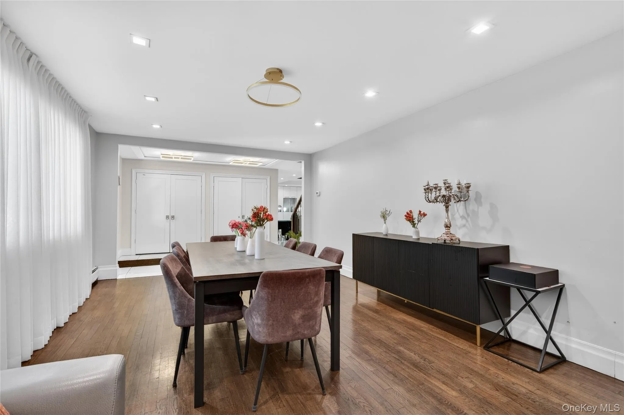 Spacious room featuring wood-finish flooring, recessed lighting, and a contemporary ceiling fixture Spacious room featuring wood-finish flooring, recessed lighting, and a contemporary ceiling fixture