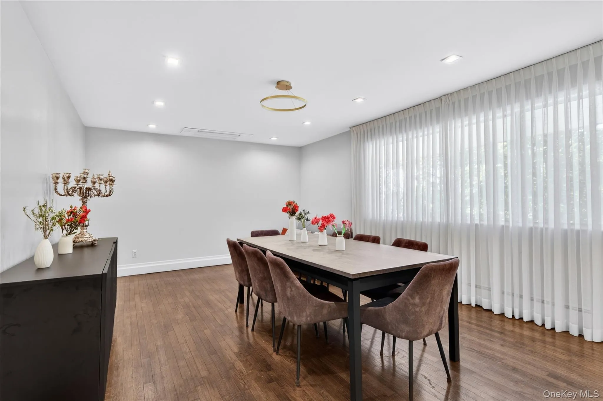 Spacious room featuring wood-finish flooring, white walls, and recessed lighting Spacious room featuring wood-finish flooring, white walls, and recessed lighting