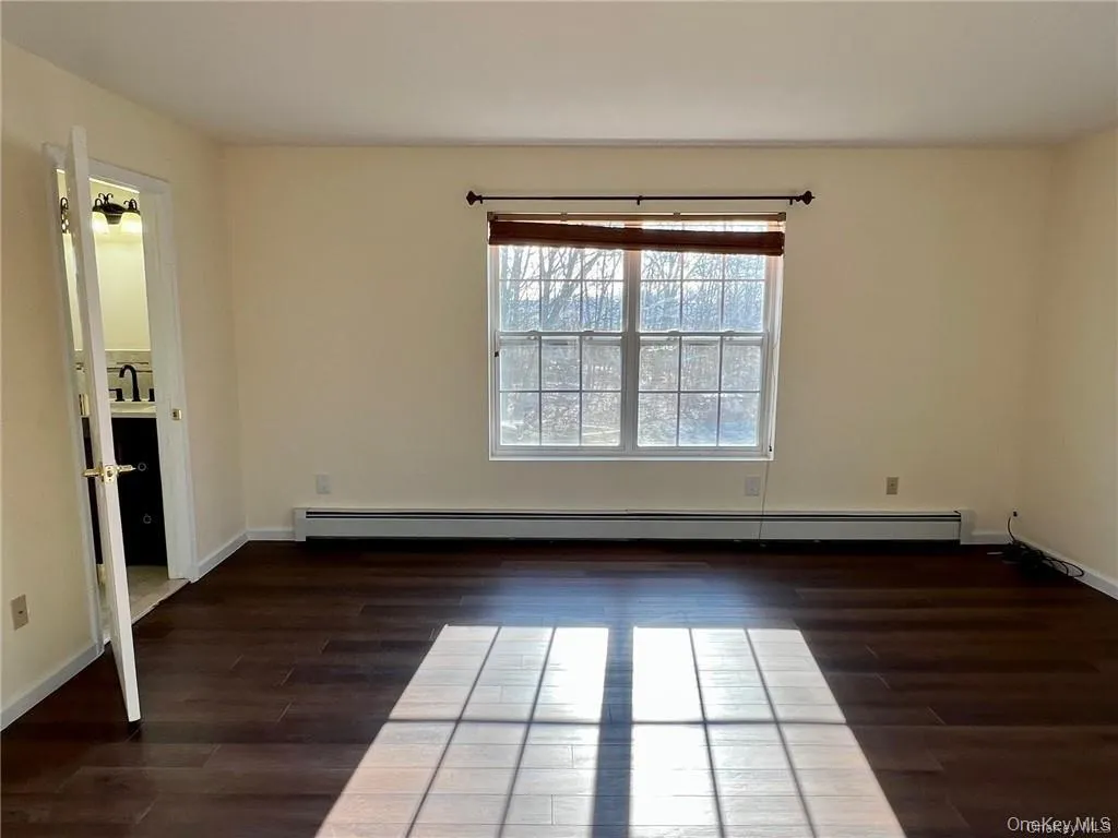 Primary bedroom feauring a baseboard heating unit, sink, and dark hardwood / wood-style flooring Primary bedroom feauring a baseboard heating unit, sink, and dark hardwood / wood-style flooring
