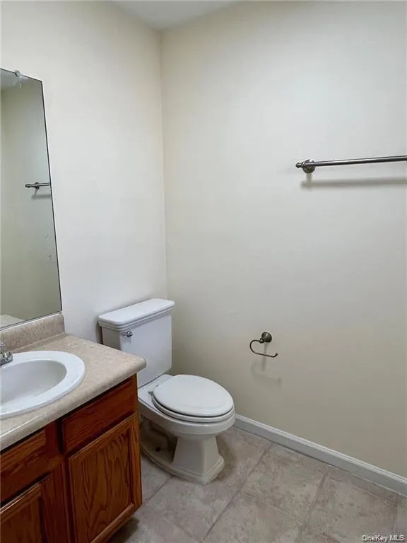 Half Bathroom featuring tile flooring, vanity, and toilet Half Bathroom featuring tile flooring, vanity, and toilet