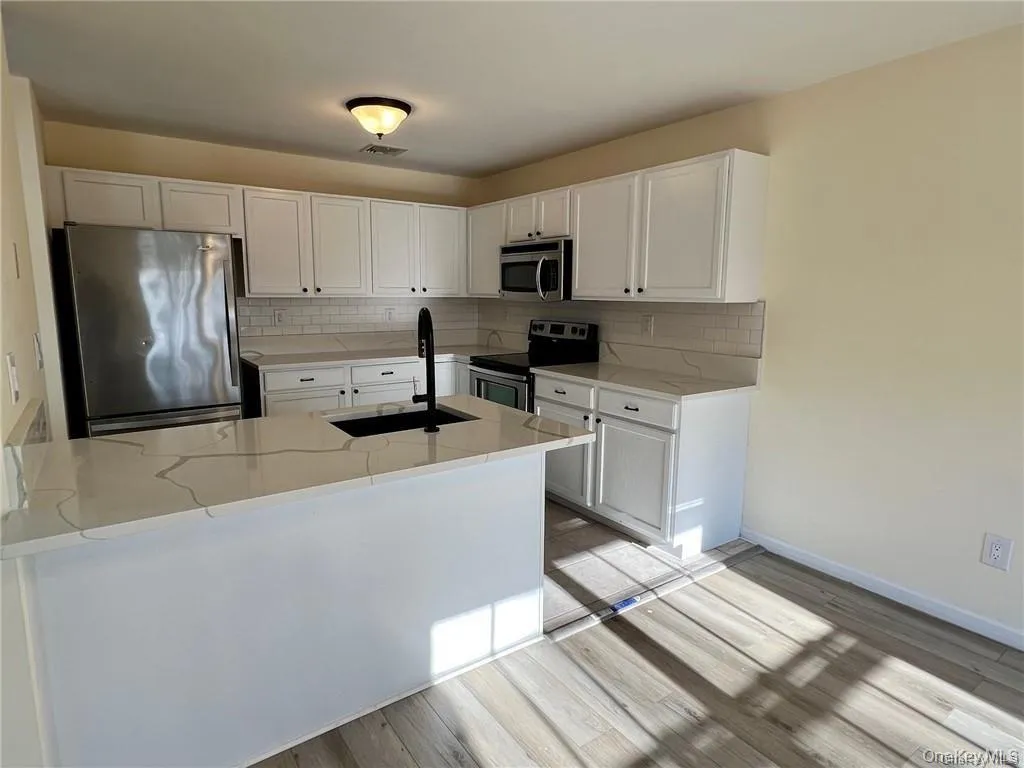 Kitchen featuring appliances with stainless steel finishes, sink, backsplash, and light stone counters Kitchen featuring appliances with stainless steel finishes, sink, backsplash, and light stone counters