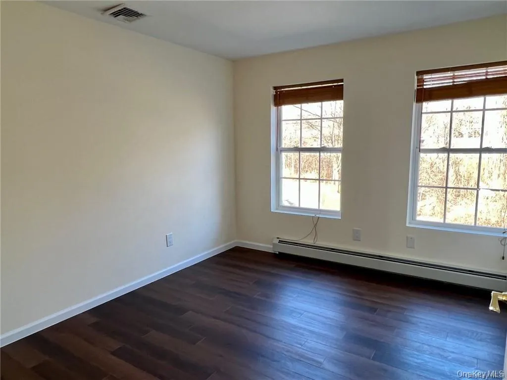 Unfurnished room with a baseboard heat and dark hardwood / wood-style floors Unfurnished room with a baseboard heat and dark hardwood / wood-style floors