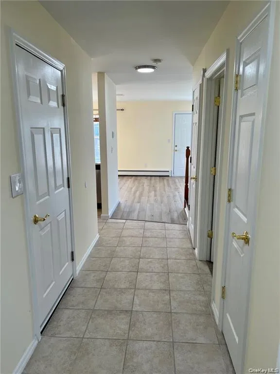 Hallway/entrance in the home featuring baseboard heating and light tile floors Hallway/entrance in the home featuring baseboard heating and light tile floors
