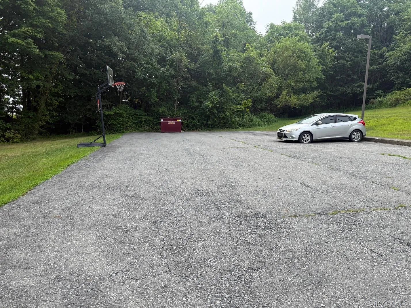 View of parking lot which holds at least 10 cars as well as features a view of trees providing privacy. View of parking lot which holds at least 10 cars as well as features a view of trees providing privacy.
