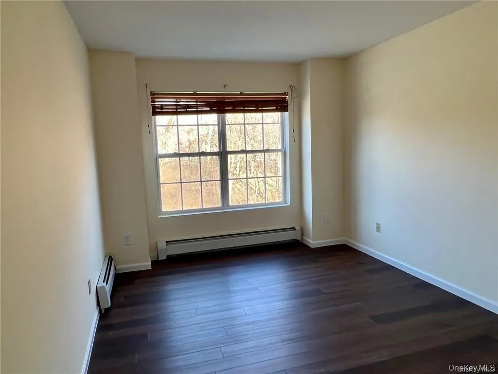 Spare room featuring a baseboard heat and dark hardwood / wood-style flooring Spare room featuring a baseboard heat and dark hardwood / wood-style flooring