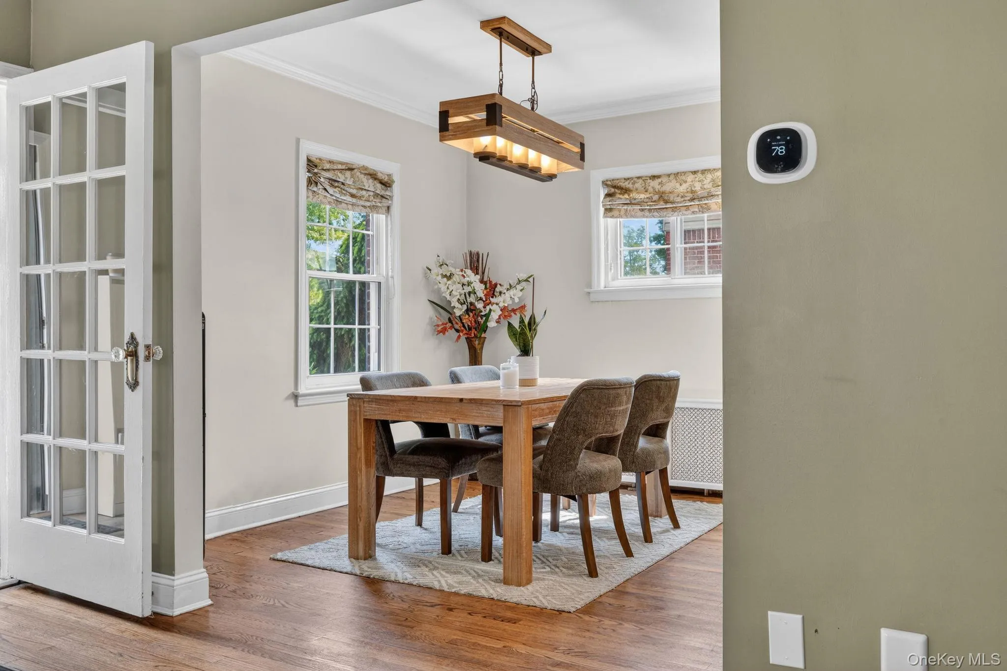 Dining space featuring wood-finish flooring, a contemporary chandelier, and multiple windows with fabric shades Dining space featuring wood-finish flooring, a contemporary chandelier, and multiple windows with fabric shades
