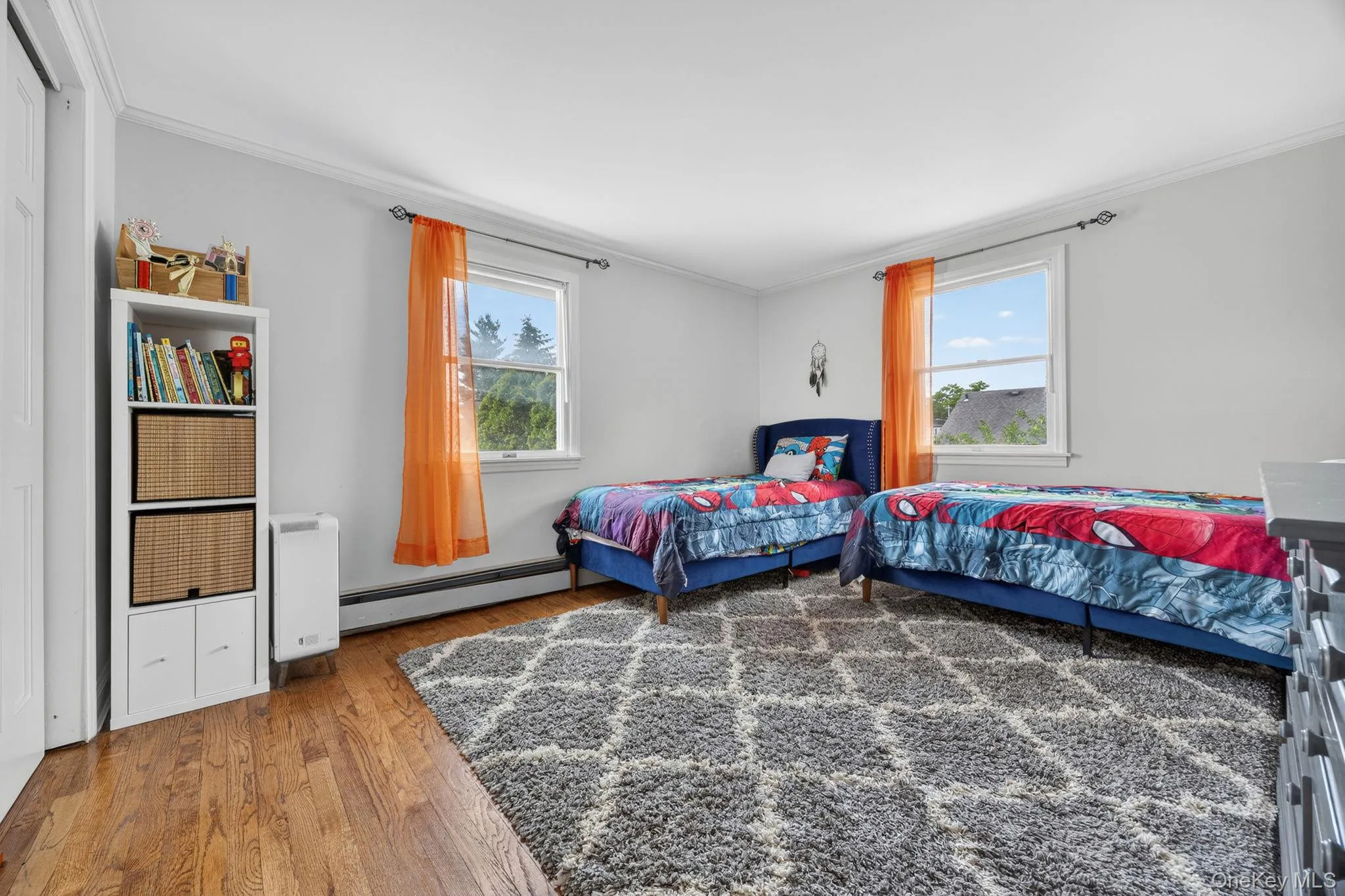 Room featuring hardwood flooring, two windows with trim, crown molding, and a built-in closet. Room featuring hardwood flooring, two windows with trim, crown molding, and a built-in closet.