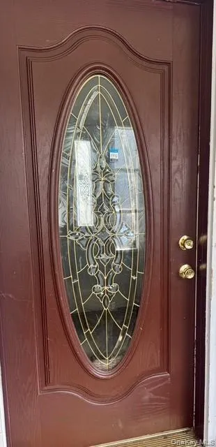 Deep red entry door with decorative oval glass insert, featuring an ornate pattern and brass-finish hardware Deep red entry door with decorative oval glass insert, featuring an ornate pattern and brass-finish hardware