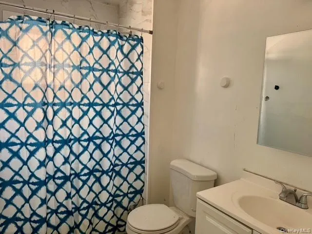 Bathroom featuring a white vanity with an integrated sink, polished chrome faucet, and a wall-mounted mirror Bathroom featuring a white vanity with an integrated sink, polished chrome faucet, and a wall-mounted mirror