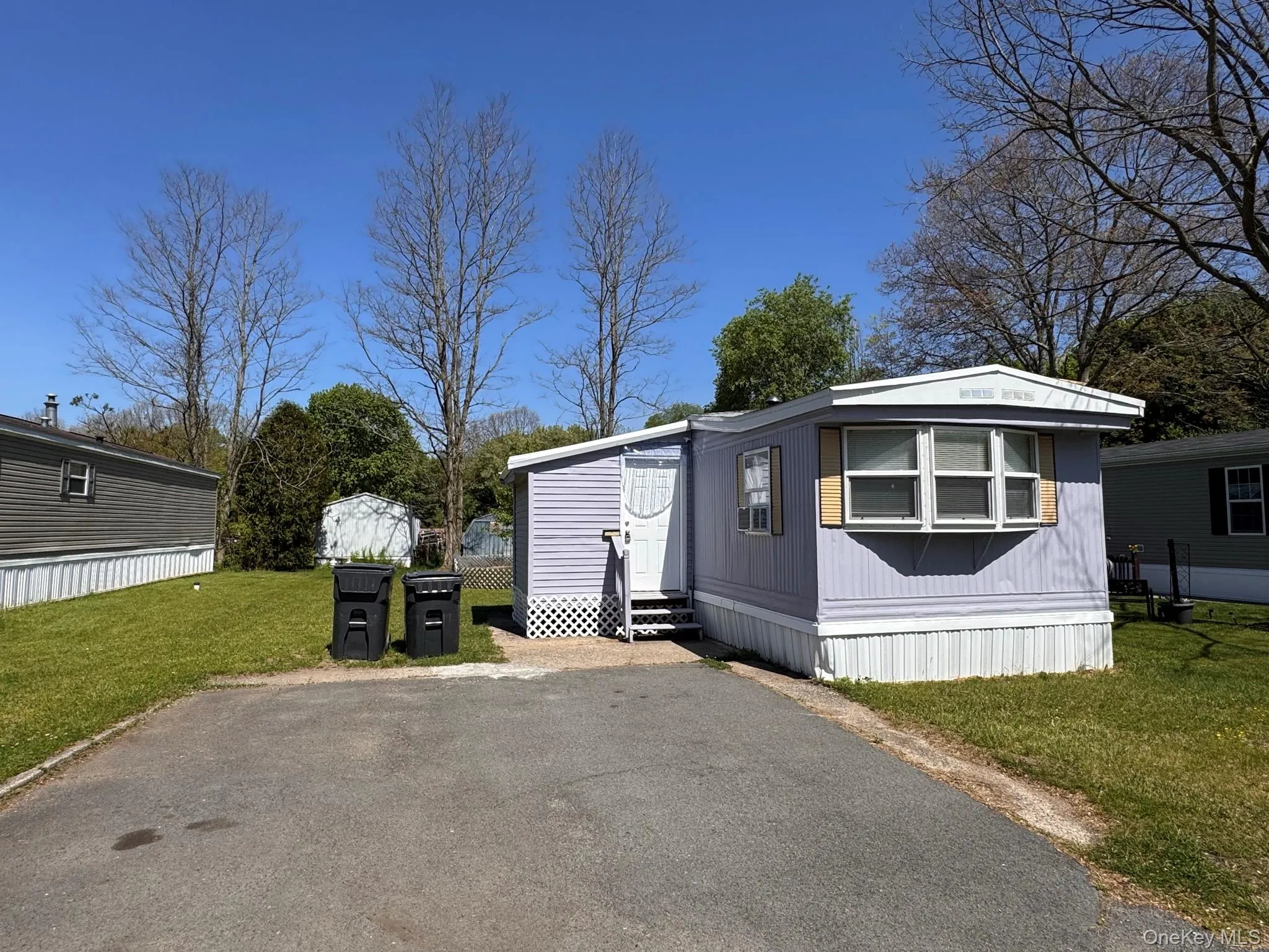 Light blue manufactured home with white trim and a front-facing window Light blue manufactured home with white trim and a front-facing window