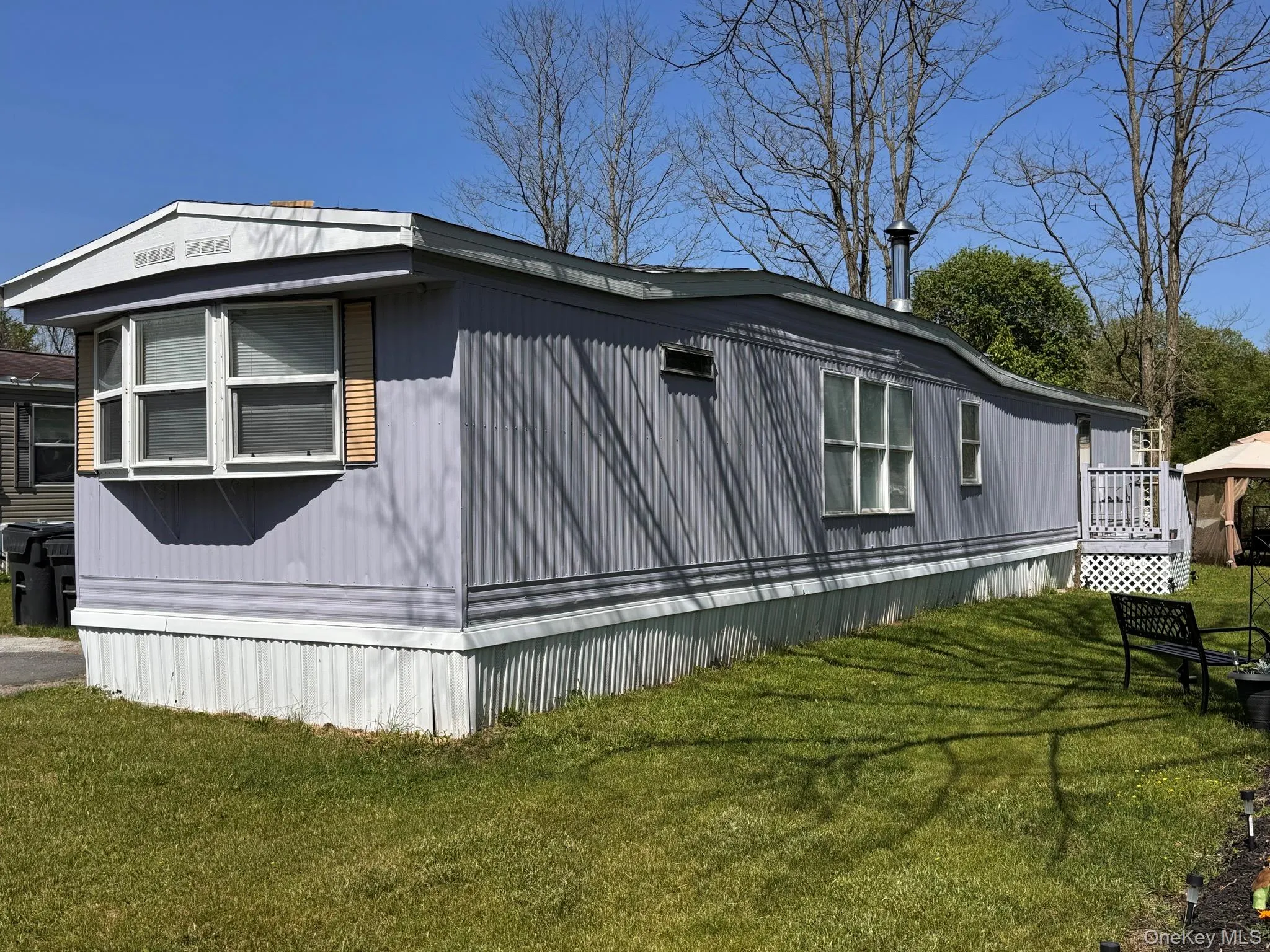 Light blue vinyl siding exterior with white window trim and a bay window featuring louvered shutters Light blue vinyl siding exterior with white window trim and a bay window featuring louvered shutters