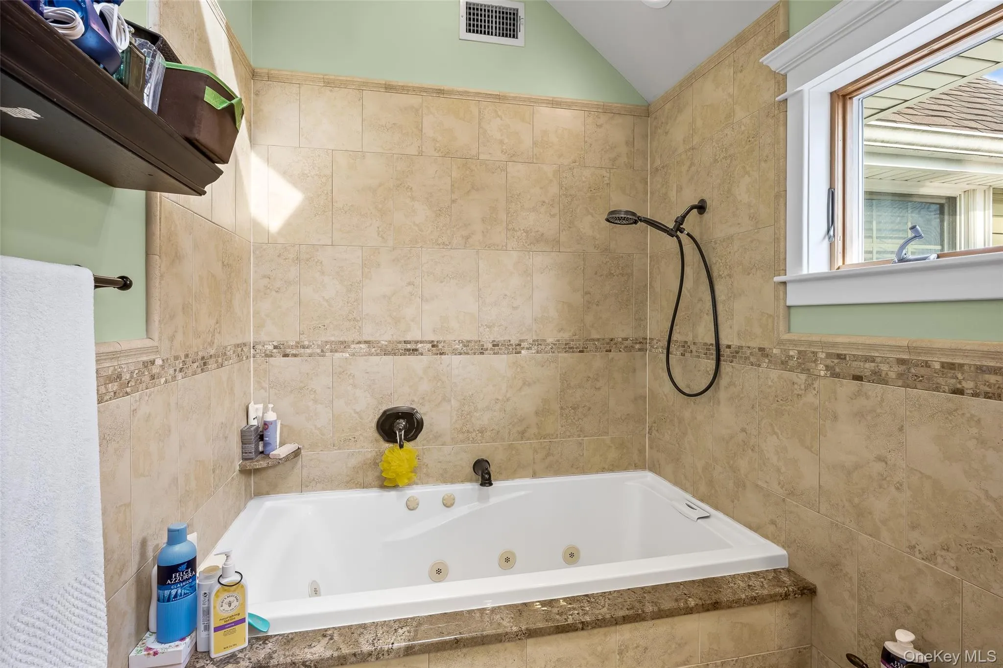 Bathroom featuring tile walls, a combined bath / shower with jetted tub, and lofted ceiling Bathroom featuring tile walls, a combined bath / shower with jetted tub, and lofted ceiling