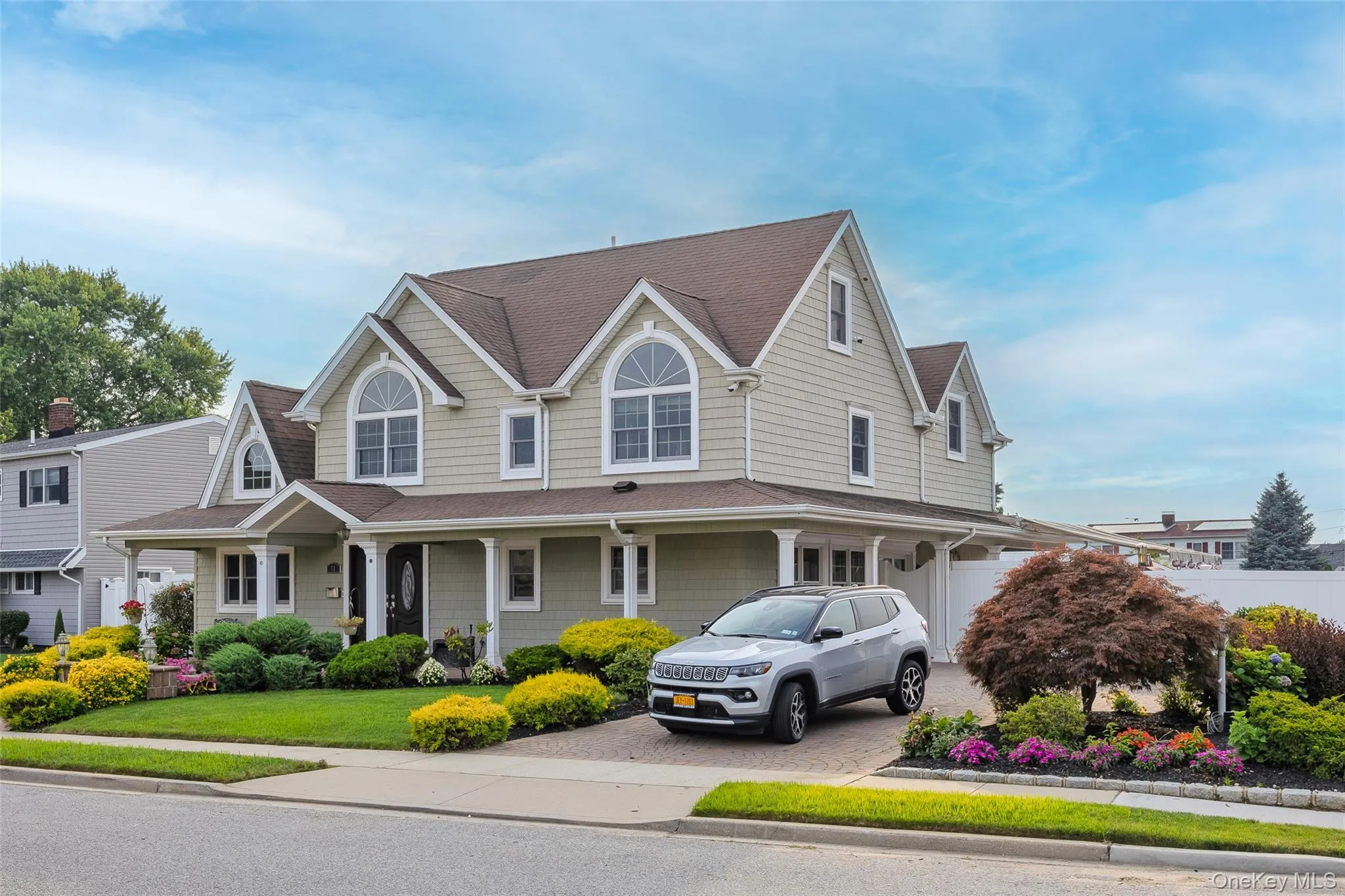 View of front facade with a porch, decorative driveway, a shingled roof, and a front yard View of front facade with a porch, decorative driveway, a shingled roof, and a front yard