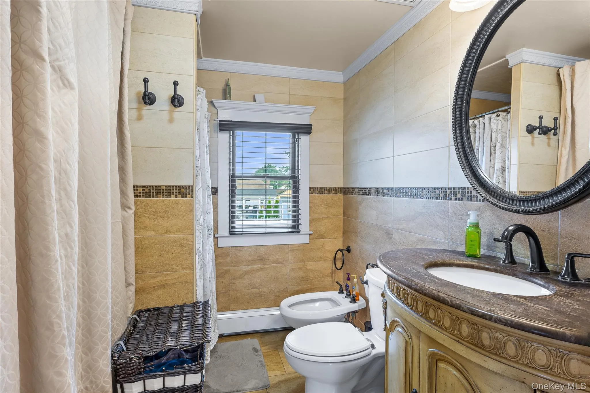 Full bath featuring tile walls, vanity, a bidet, a baseboard heating unit, and crown molding Full bath featuring tile walls, vanity, a bidet, a baseboard heating unit, and crown molding