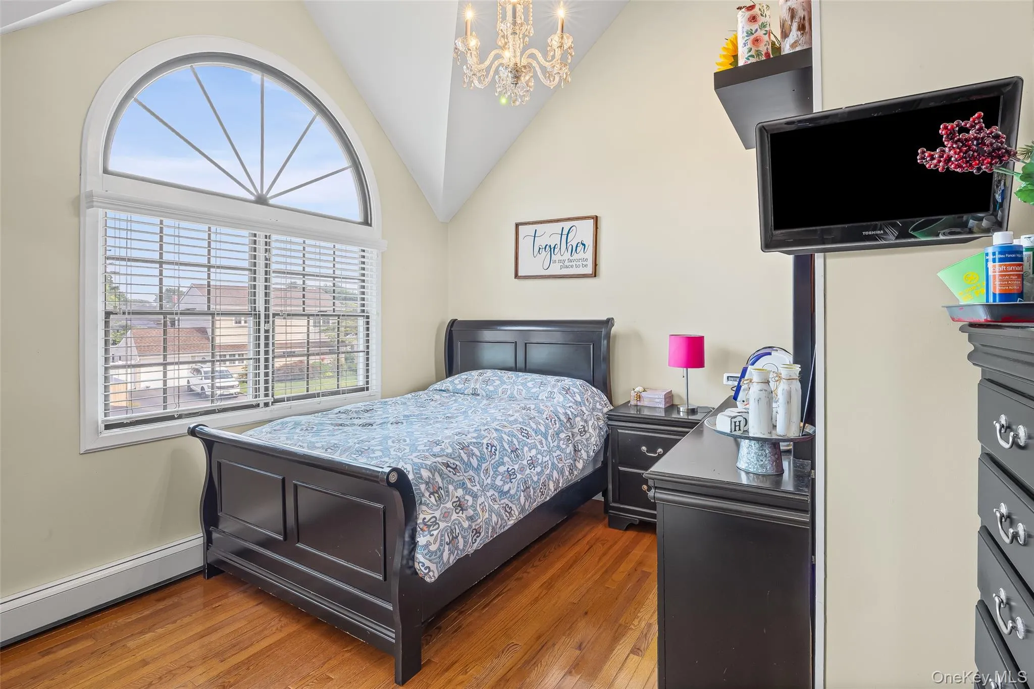 Bedroom featuring lofted ceiling, wood finished floors, baseboard heating, and a chandelier Bedroom featuring lofted ceiling, wood finished floors, baseboard heating, and a chandelier