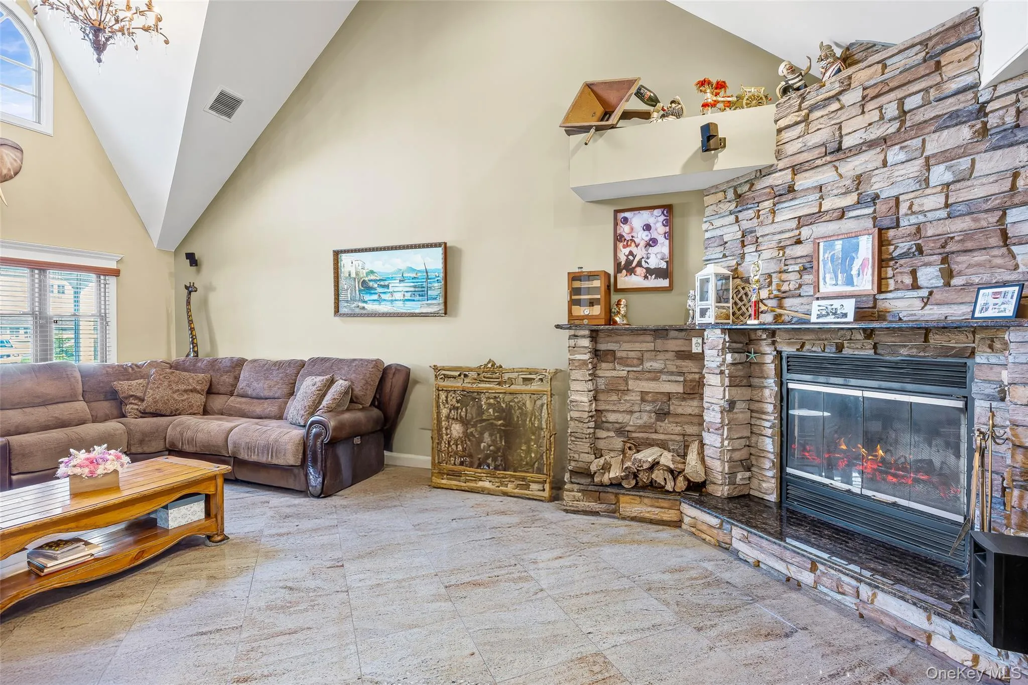 Living area with high vaulted ceiling, plenty of natural light, a fireplace, and a chandelier Living area with high vaulted ceiling, plenty of natural light, a fireplace, and a chandelier