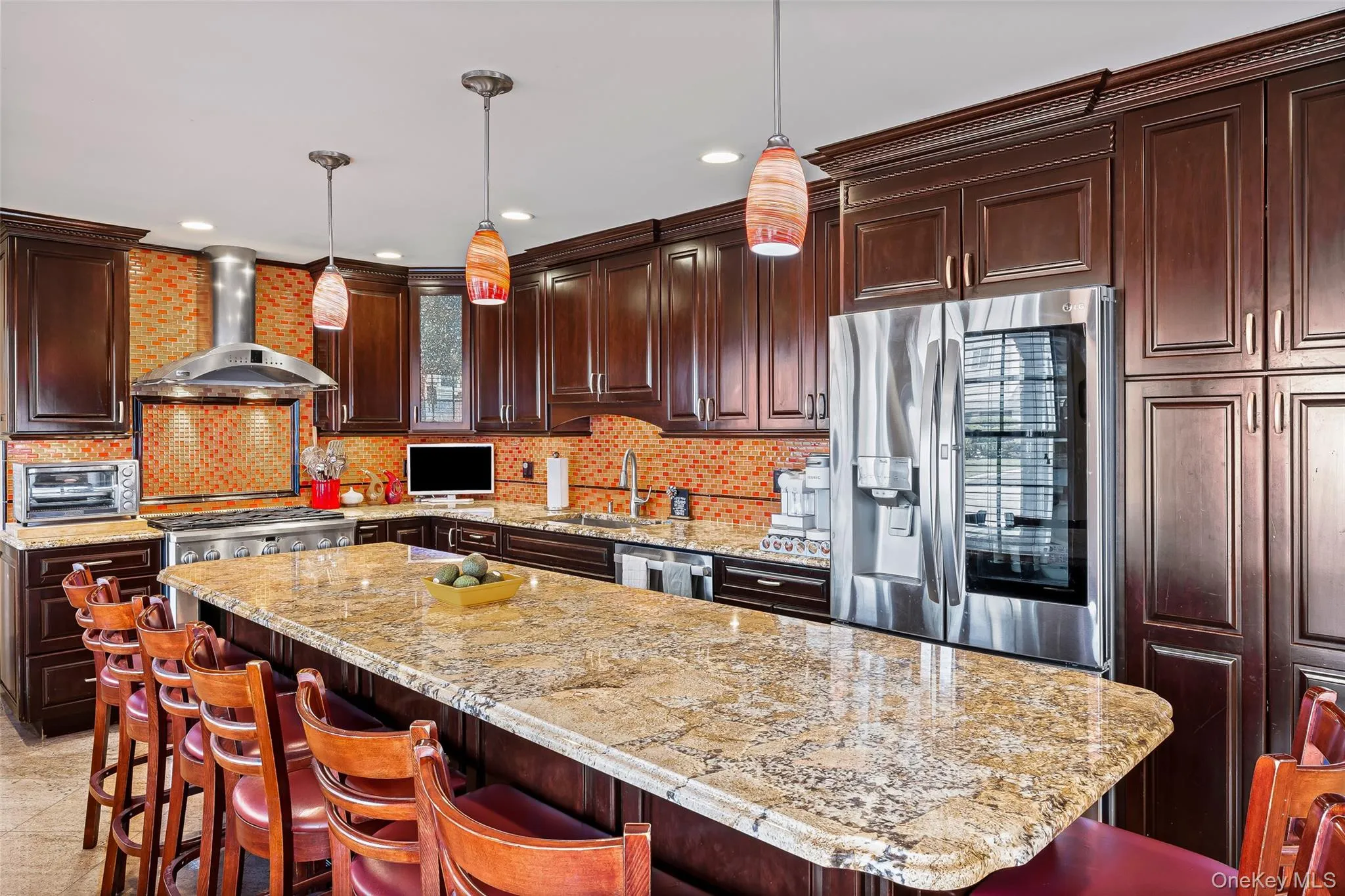 Kitchen with a breakfast bar area, dark brown cabinets, appliances with stainless steel finishes, wall chimney range hood, and recessed lighting Kitchen with a breakfast bar area, dark brown cabinets, appliances with stainless steel finishes, wall chimney range hood, and recessed lighting