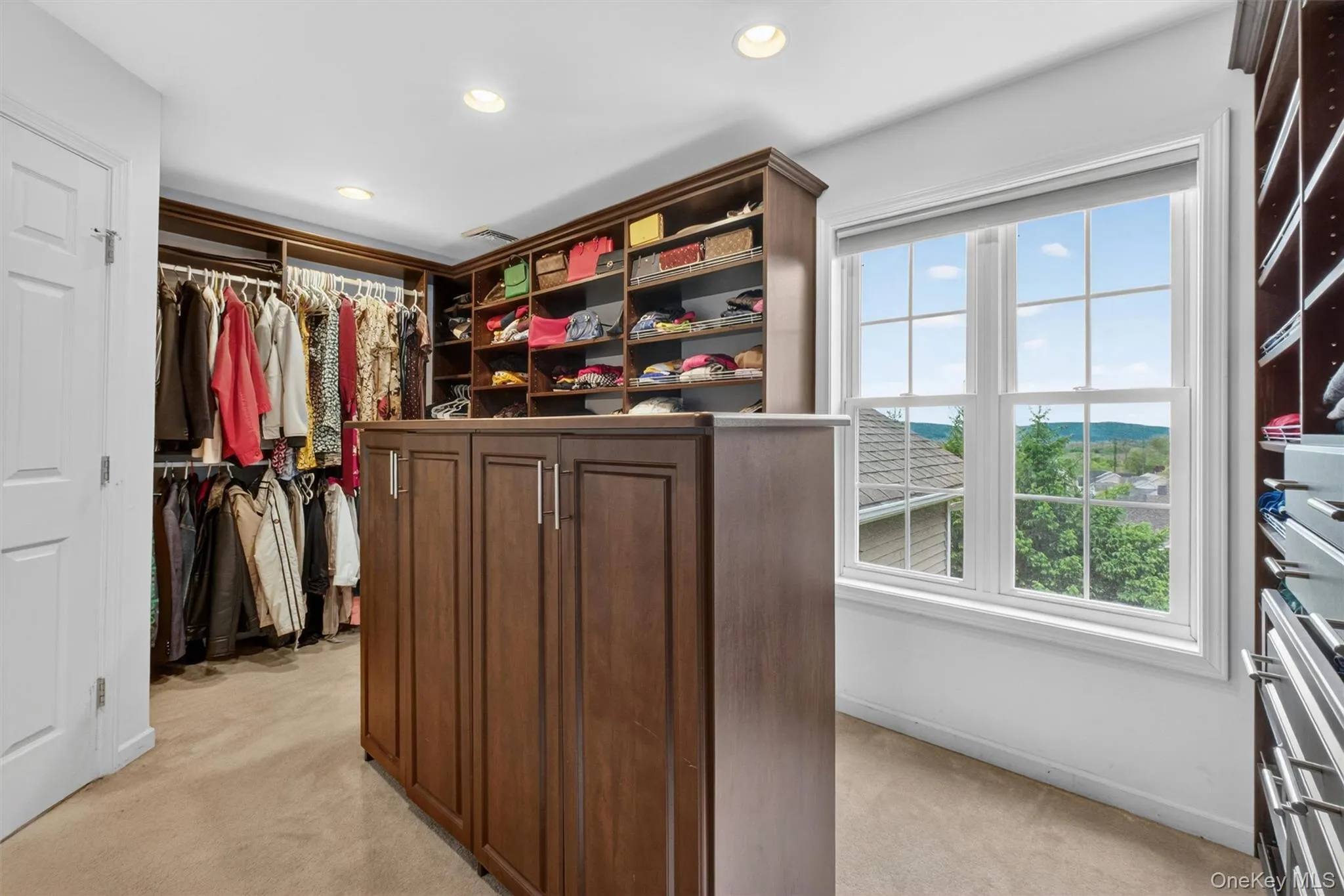 Boutique-style primary dressing room with oversized walk-in layout, custom California Closets, and center island. Boutique-style primary dressing room with oversized walk-in layout, custom California Closets, and center island.