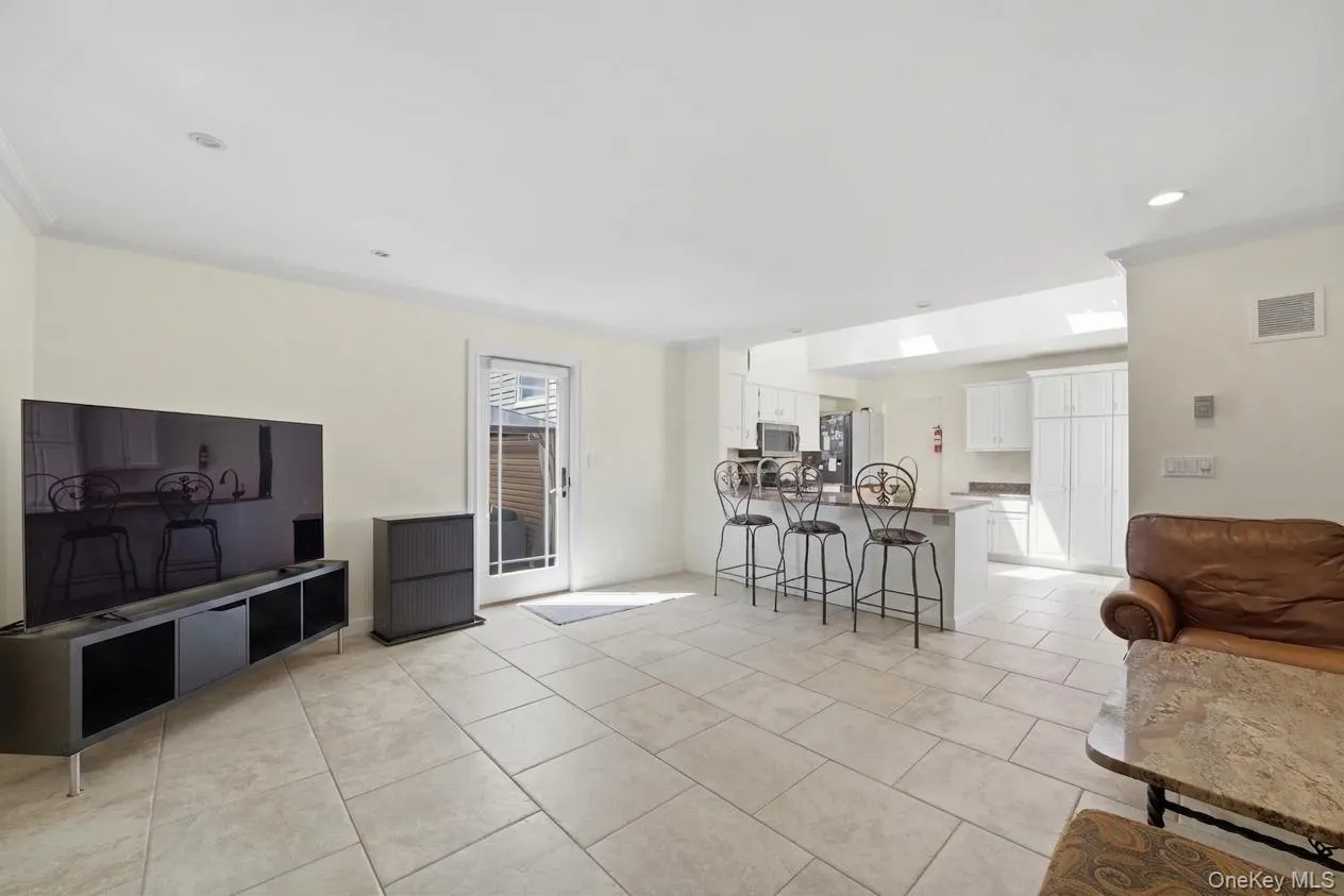 Spacious room with large format tile flooring, crown molding, and recessed lighting Spacious room with large format tile flooring, crown molding, and recessed lighting