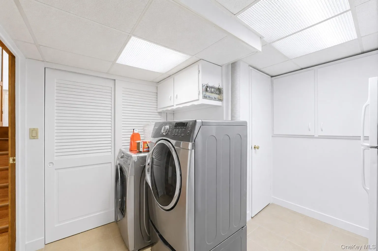 Dedicated laundry area featuring white cabinetry, light-toned flooring, and contemporary overhead lighting Dedicated laundry area featuring white cabinetry, light-toned flooring, and contemporary overhead lighting
