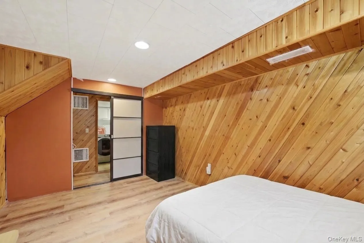Basement bedroom featuring diagonal wood paneling and wood-finish flooring Basement bedroom featuring diagonal wood paneling and wood-finish flooring