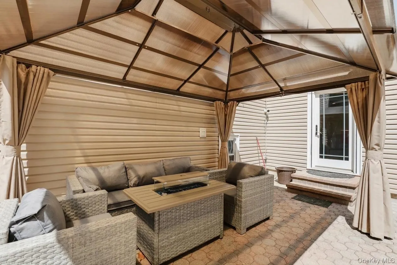 Patio area featuring a metal-framed gazebo with a fabric canopy and privacy drapes Patio area featuring a metal-framed gazebo with a fabric canopy and privacy drapes