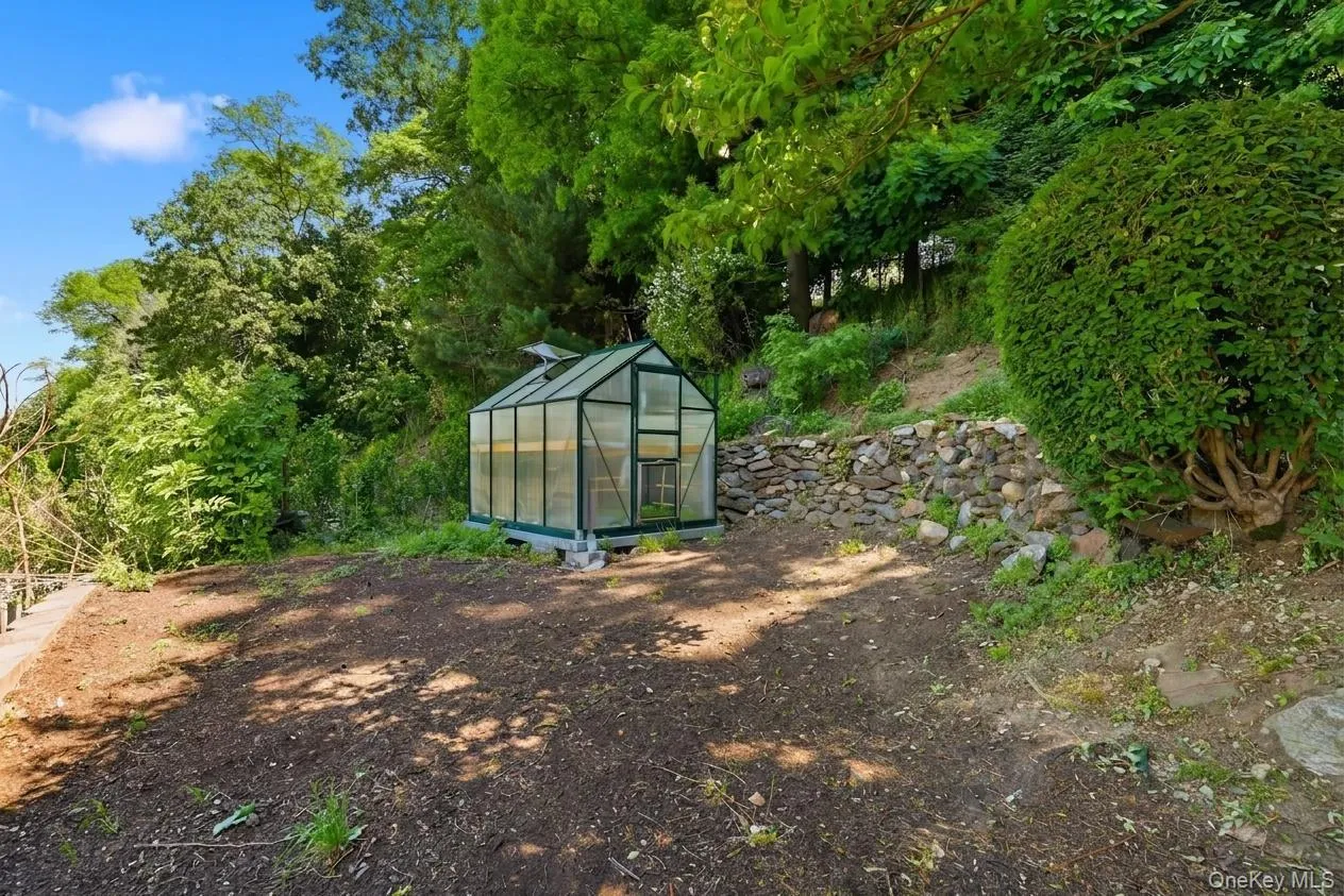 Standalone greenhouse structure with a sloped glass roof and clear paneling Standalone greenhouse structure with a sloped glass roof and clear paneling