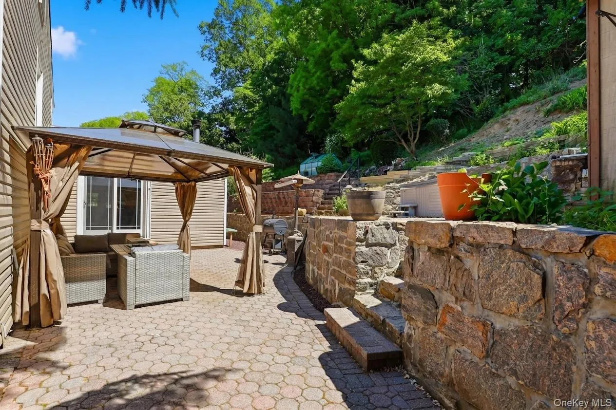 Expansive paver patio featuring a permanent gazebo structure with a hardtop roof and drapes Expansive paver patio featuring a permanent gazebo structure with a hardtop roof and drapes