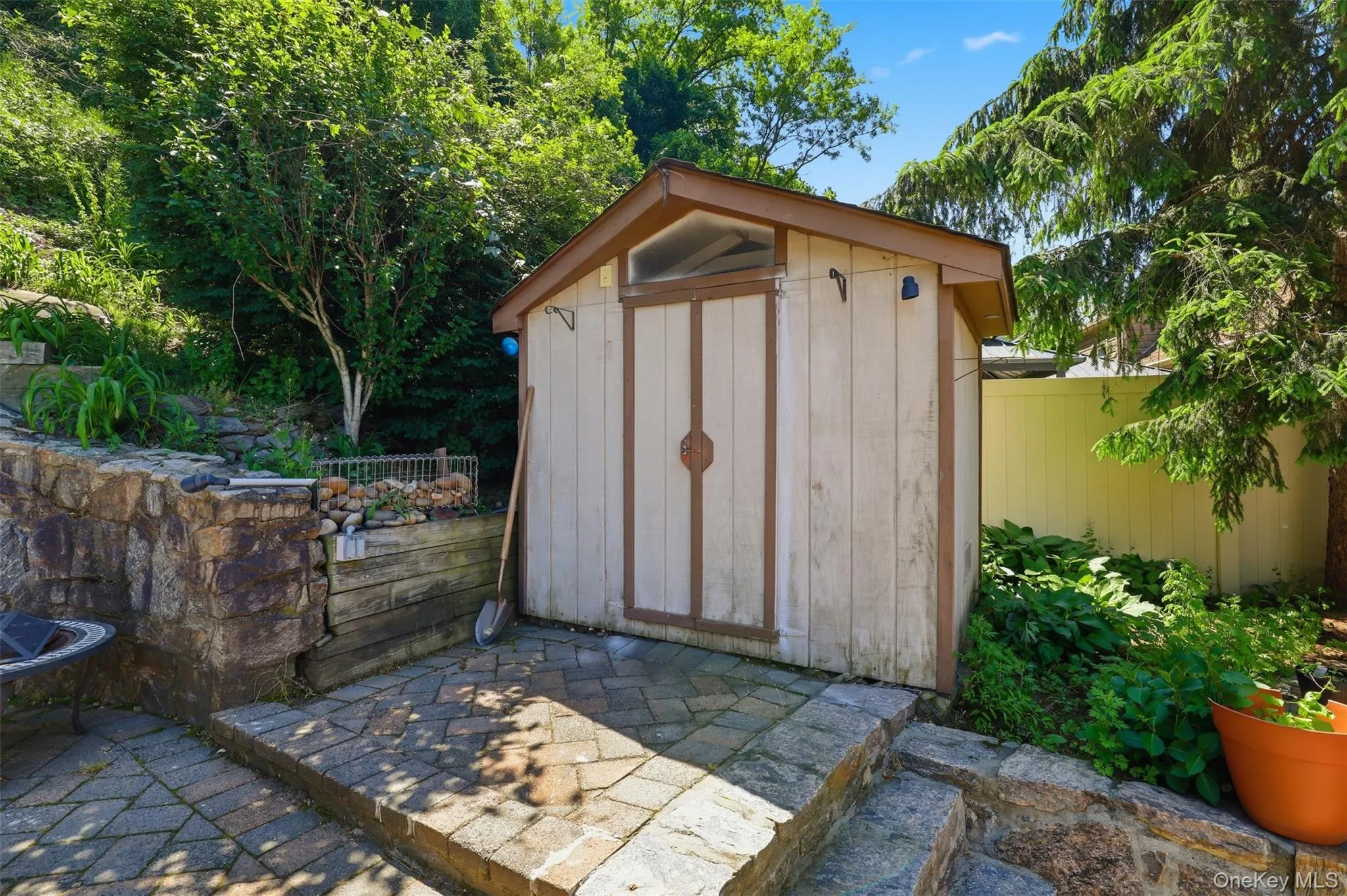 Exterior storage shed with a peaked roof, set on a paver patio Exterior storage shed with a peaked roof, set on a paver patio